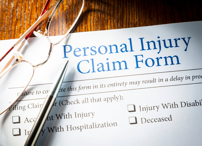 Personal Injury Claim form with pen and glasses